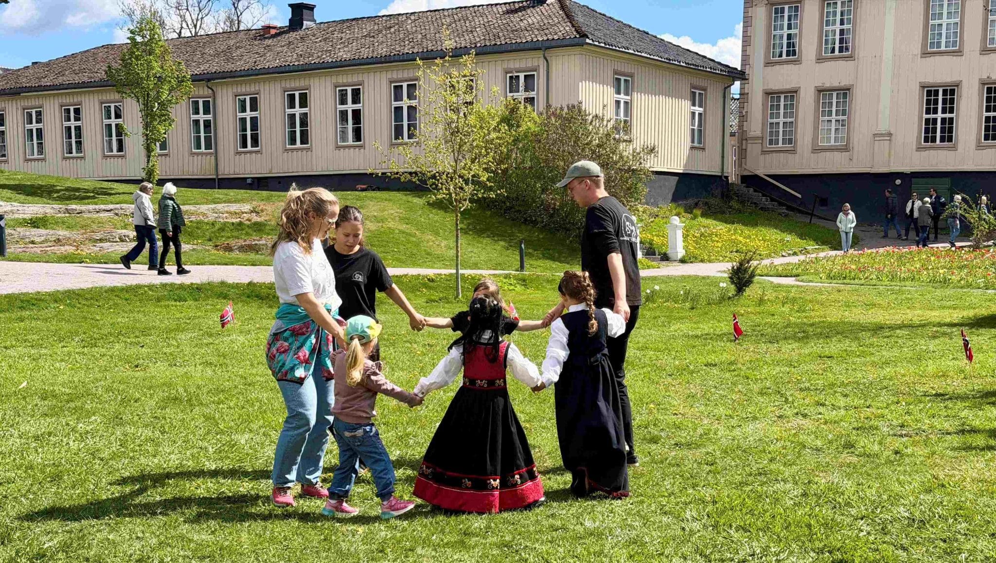 Askeladden leikarring - Småhalling, dans for små føtter. Voksne og barn danser på gressplenen utenfor herskapshuset i Brekkeparken
