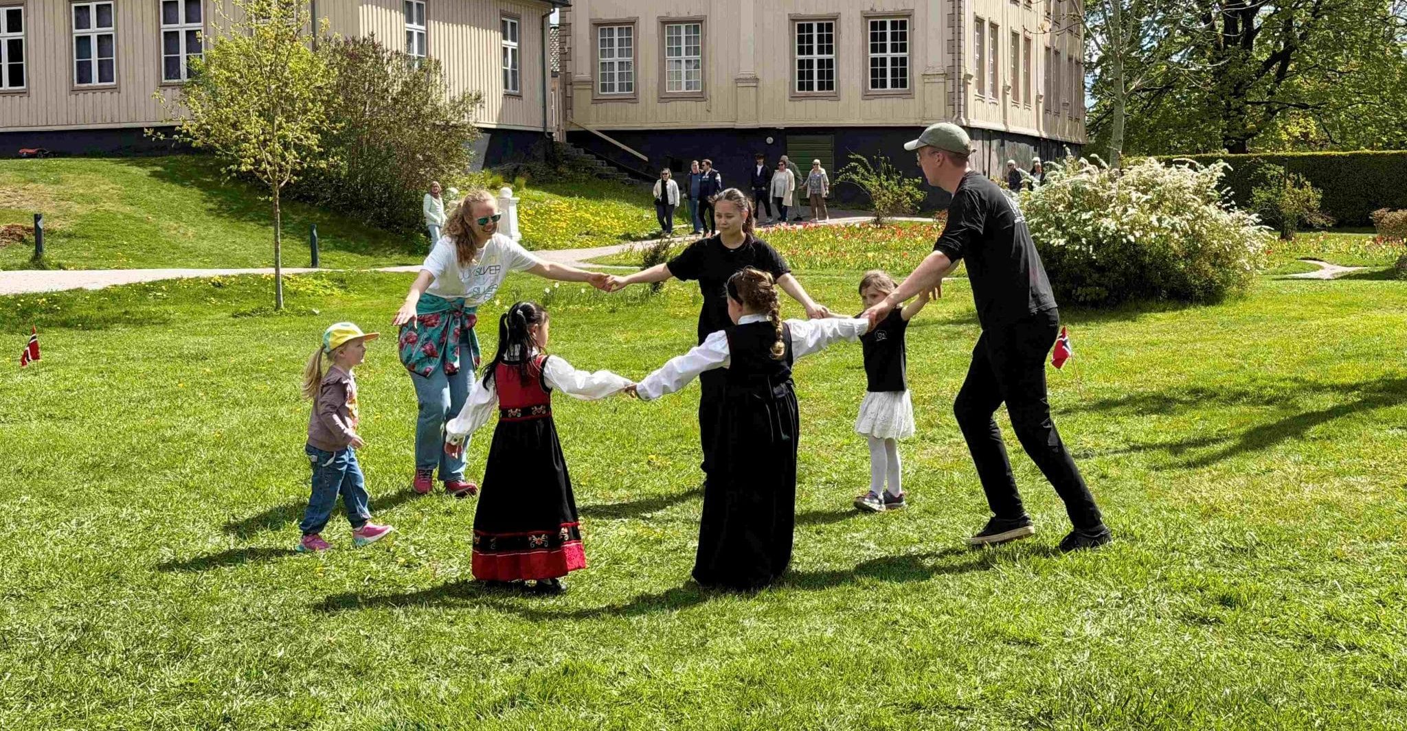 Askeladden leikarring - Småhalling, dans for små føtter. Voksne og barn danser på gressplenen utenfor herskapshuset i Brekkeparken