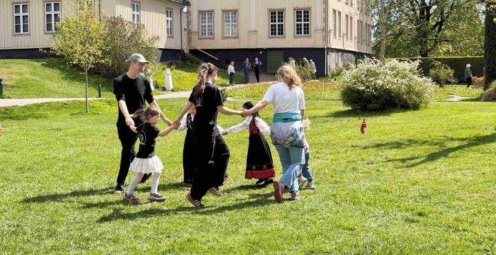 Askeladden leikarring - Småhalling, dans for små føtter. Voksne og barn danser på gressplenen utenfor herskapshuset i Brekkeparken