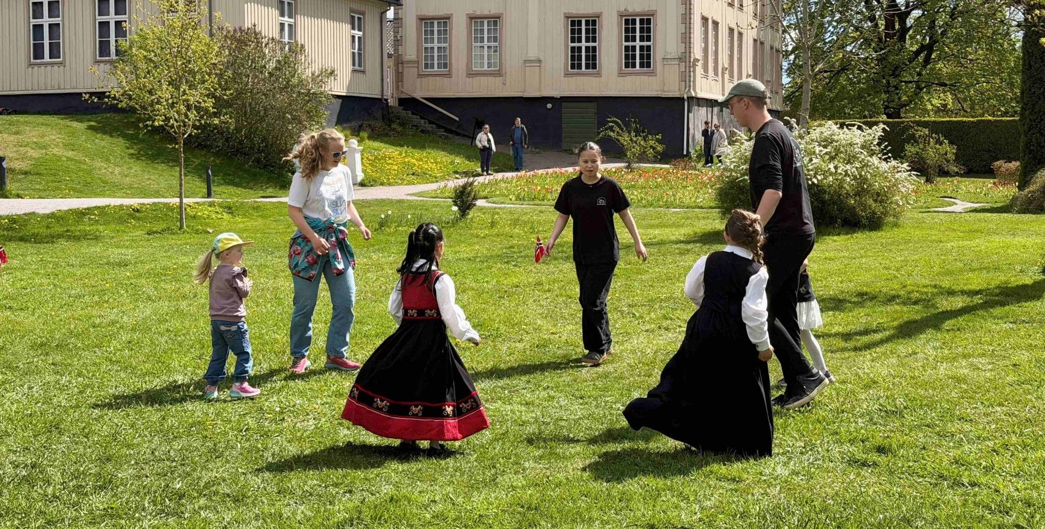 Askeladden leikarring - Småhalling, dans for små føtter. Voksne og barn danser på gressplenen utenfor herskapshuset i Brekkeparken