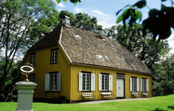 Berg-Kragerø museum, lystgården. Bildet viser den okergule gårdsbygningen, hovedhuset sommerstid. Soluret står utenfor til venstre.