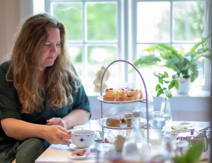 Litterær afternoon tea på Henrik Ibsen museum. En dame sitter og drikker te ved et bord med afternoon tea-pådekking.