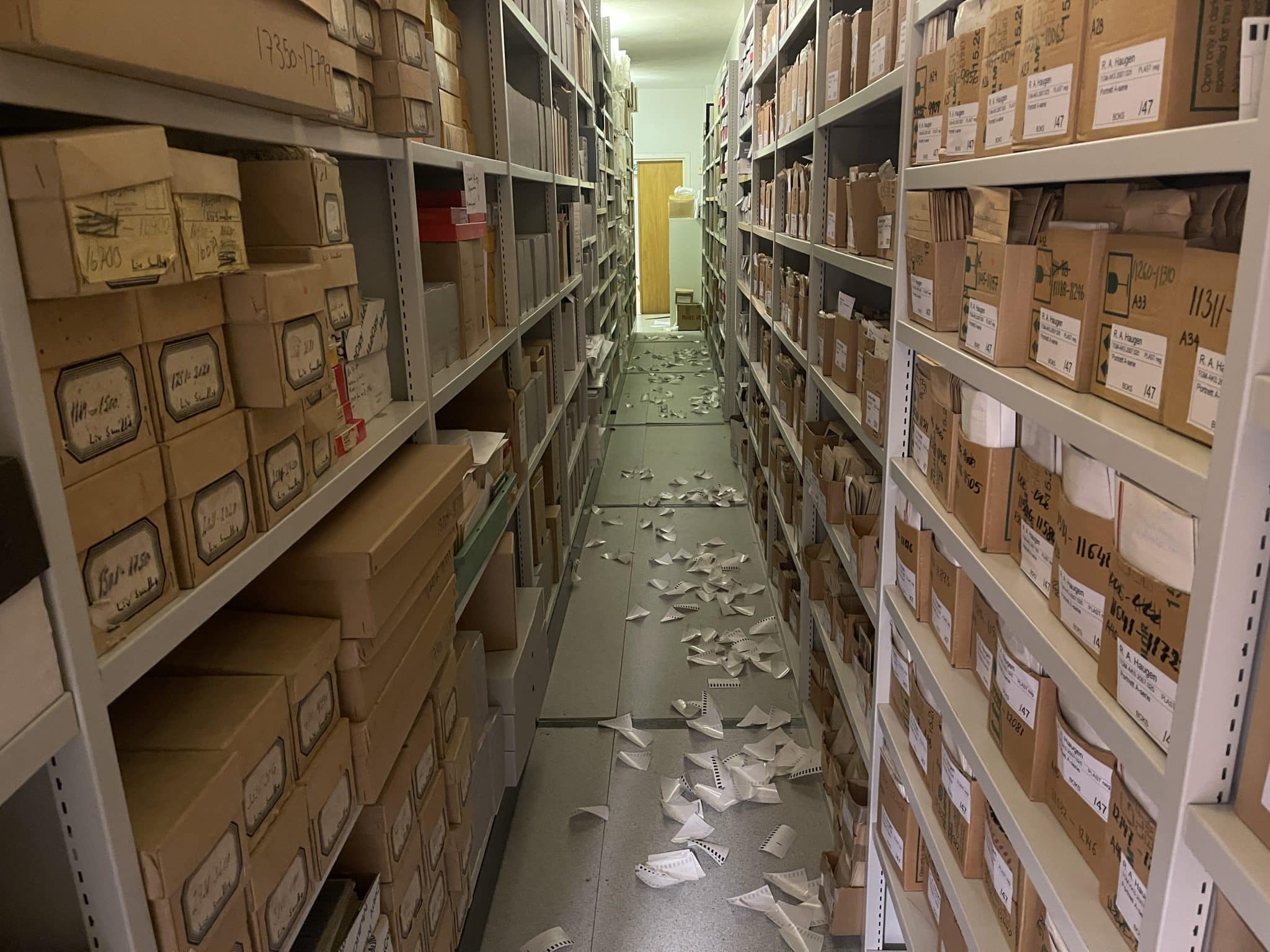 Et gammelt arkiv i en kjeller. Hyller med arkivmateriale