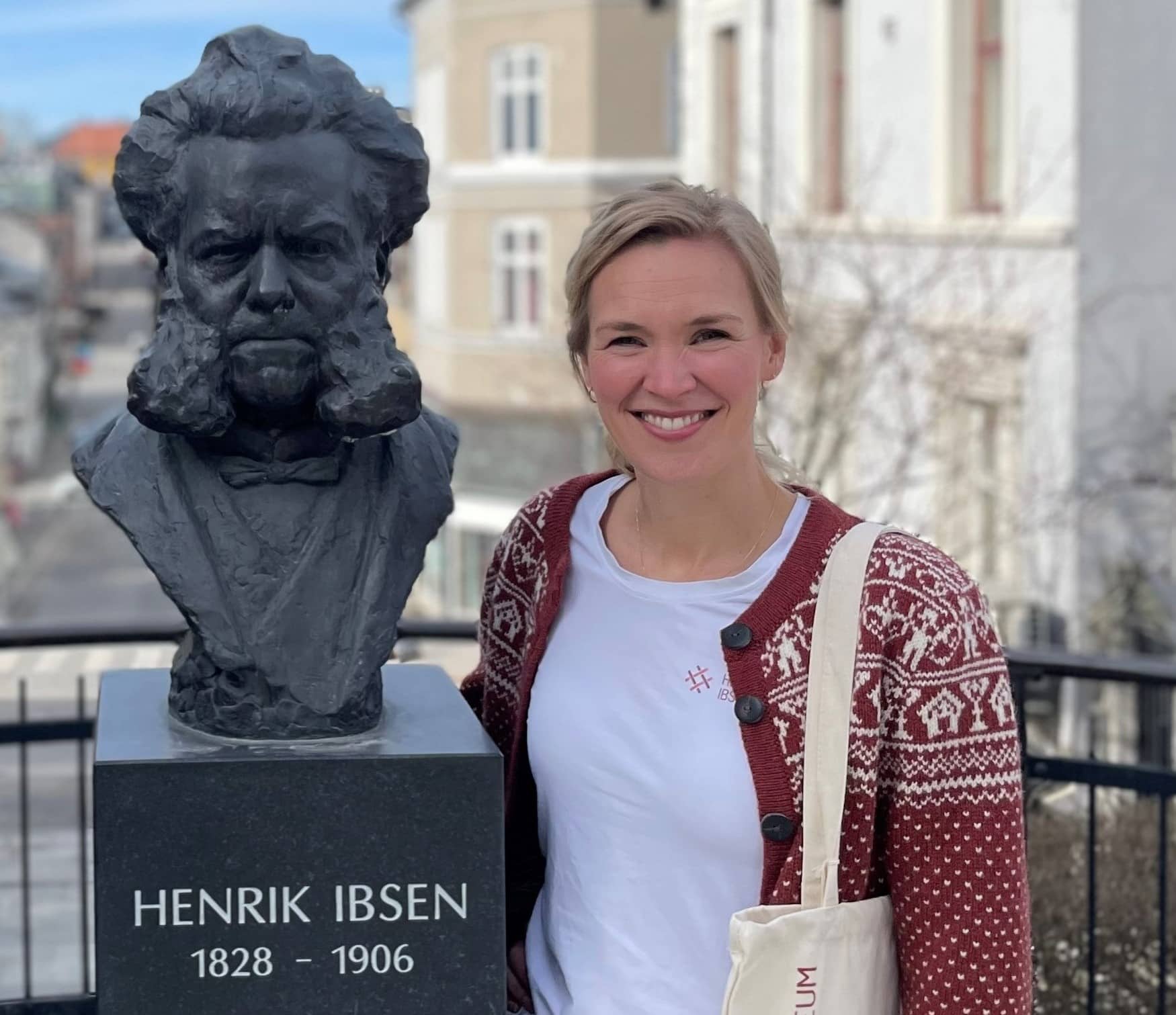 Kreativ leder ved Henrik Ibsen museum, Linnea Dale poserer ved Ibsenbysten