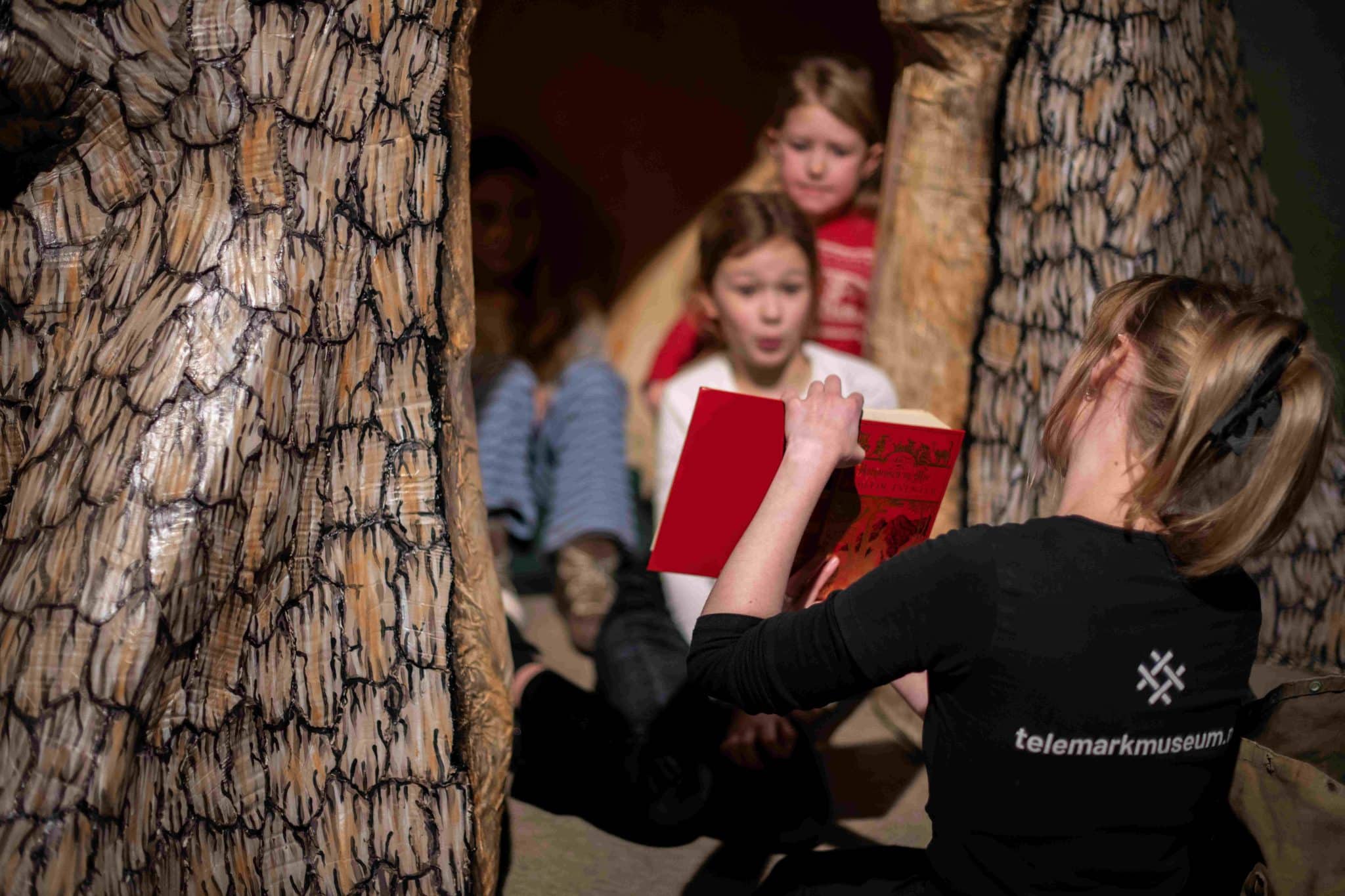 Lesestund i Eventyrlige Kittelsen. En omviser fra Telemark museum viser frem noen sider i en eventyrbok. Barna følger med
