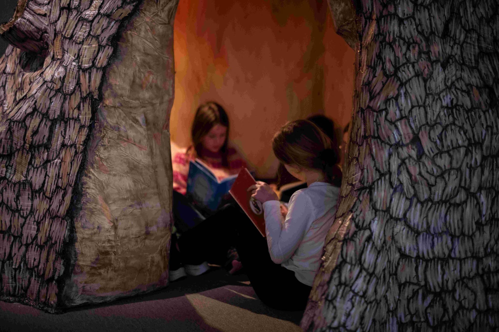 Lesestund i Eventyrlige Kittelsen, barn som sitter og leser inne i en trekulisse