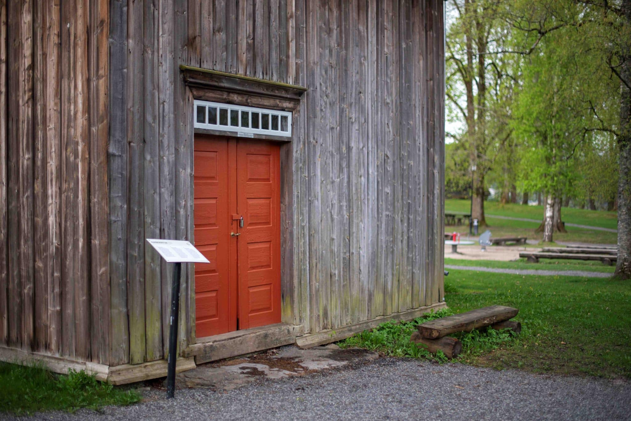 Rambergstua utvendig, inngangspartiet. Huset er kledd med grå panel, inngangsdøra er dobbel med rustrød farge