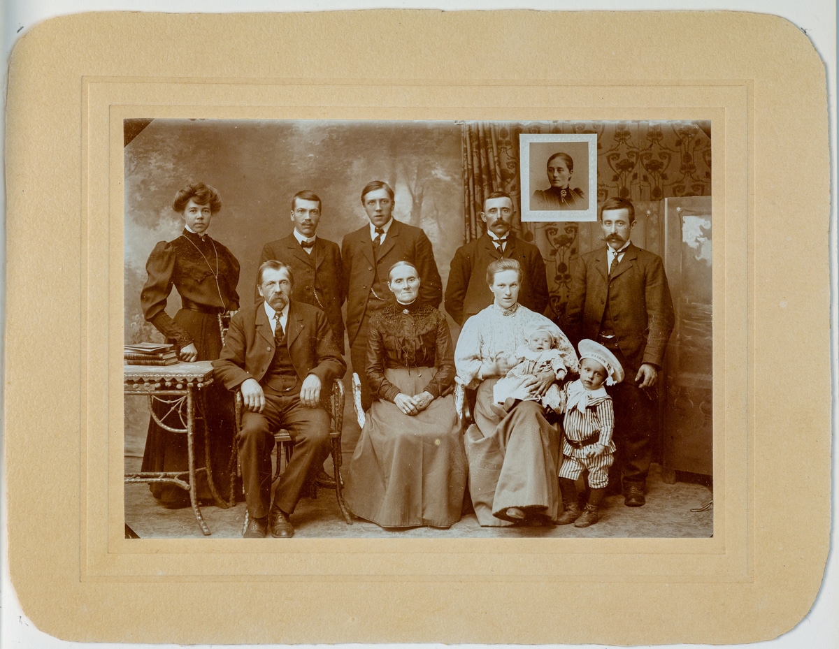 Foto av familien Lunde og Sørensen. Gammelt sort-hvittbilde i bruntoner. Fem personer står oppstilt på rekke bakerst og tre personer sitter på stoler foran