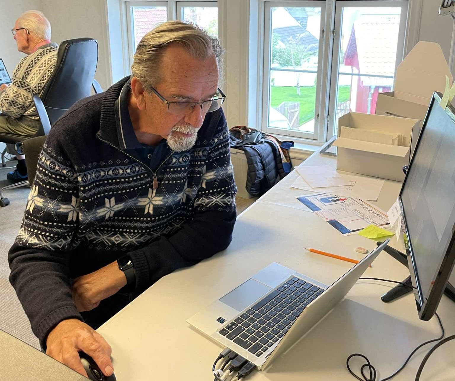 Medlemmer i Gjerpen historielag registrerer bilder på Telemark museums arkiv. En mann sitter og jobber ved en pc