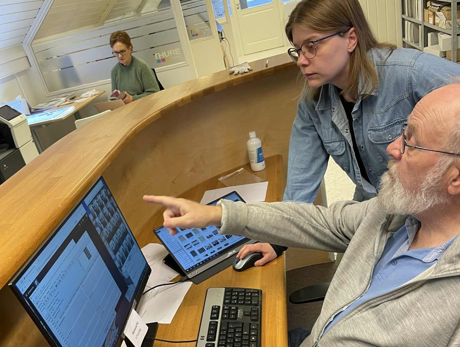 Gjerpen historielag hjelper Telemark museum med bilderegistrering. Fotoarkivar Ida Pedersen hjelper en av medlemmene som jobber med gamle bilder på en pc
